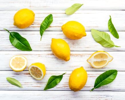 Fresh lemons and  leaves on a rustic white wooden background photo