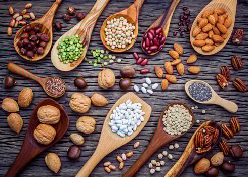 Legumes and nuts in spoon on a dark wood background photo