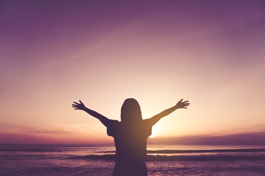 Woman raises hands up to the sky photo