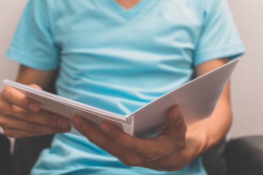 A man in a blue shirt is holding a book photo