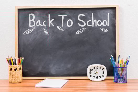 A chalkboard with school supplies on a wooden table, back to school and education concept photo