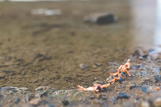 Miniature people wearing swimsuits relaxing on a beach, summer concept photo
