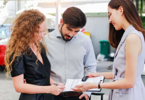 Young couple leases a new car from the showroom and is serviced by a salesperson photo