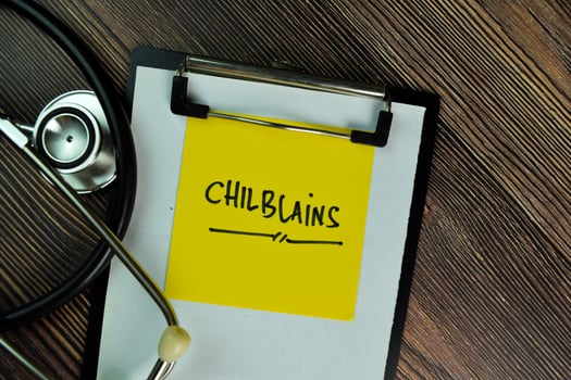 Chilblains written on sticky note isolated on wooden table photo