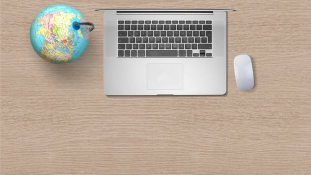 Globe with computer laptop on white paper on wooden background photo
