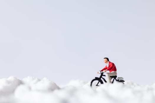 Miniature travelers riding bicycles in the snow, winter background concept photo