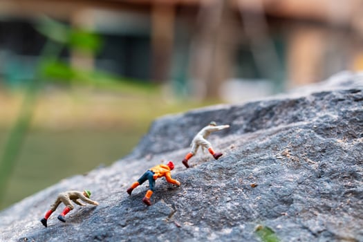 Miniature hikers climbing up on a rock, sports and leisure concept photo