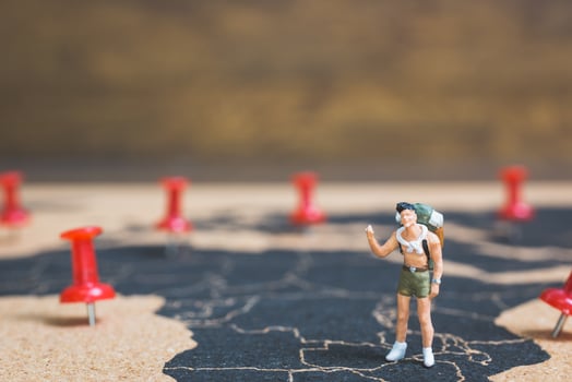 Miniature backpacker walking on a world map, tourism and travel concept photo