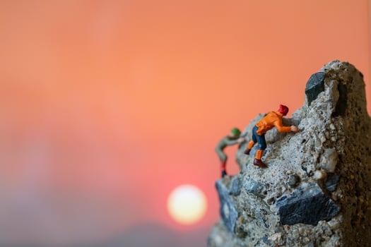 Miniature hikers climbing up on a rock, sports and leisure concept photo