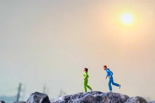 Miniature people running on a rock cliff with nature background, health and lifestyle concept photo
