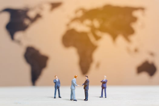 Miniature businessmen standing by a world map background, growing a business concept photo