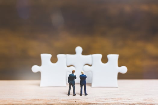 Miniature businessmen standing on jigsaws with a wooden background, business concept photo