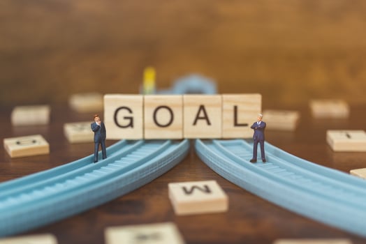 Miniature businessmen standing on wooden blocks with the word Goal, business career growth concept photo