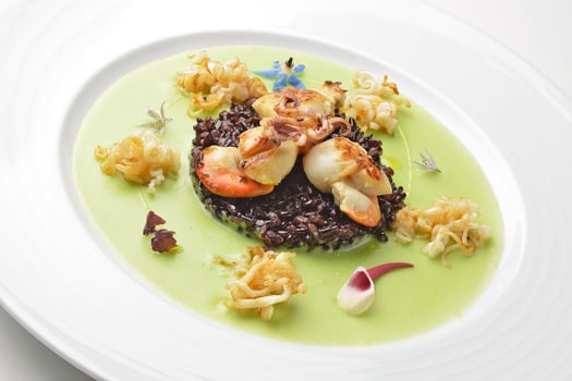 Appetizer braised scallops and black rice on pea cream photo