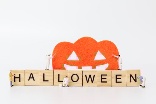 Miniature workers teaming up to create Halloween party props with wooden blocks with the text Halloween on a white background photo