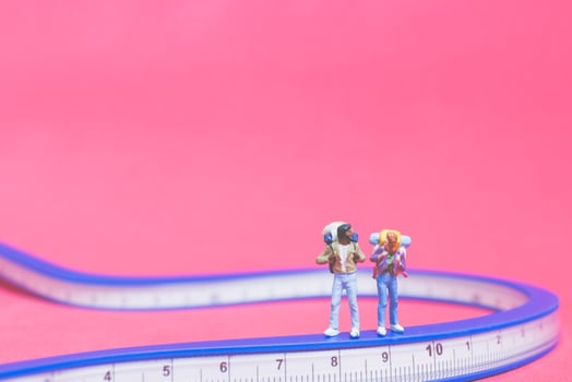 Miniature couple of travelers on a bridge with a pink background photo