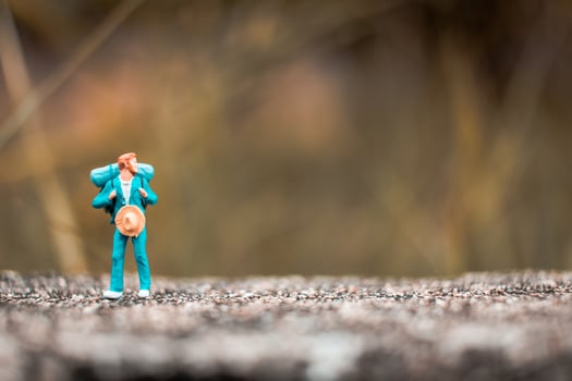 Miniature backpacker standing on a concrete floor with a bokeh nature background photo