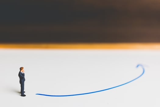 Miniature businessman standing on an arrow pathway, business decision concept photo