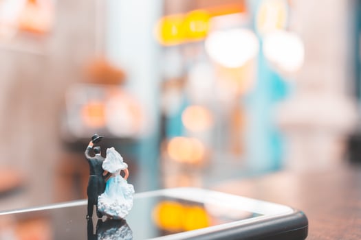 Miniature couple standing on a smartphone, love concept photo