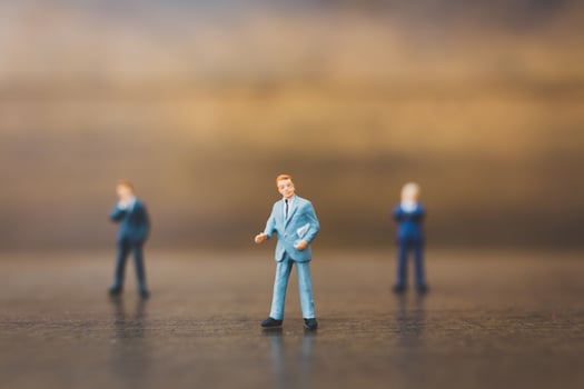 Miniature businesspeople standing on a wooden background photo