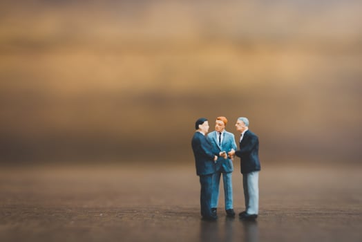 Miniature businesspeople standing on a wooden background photo