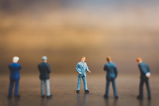 Miniature businesspeople standing on a wooden background photo