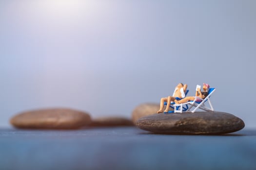 Miniature people sunbathing on a beach, summertime concept photo