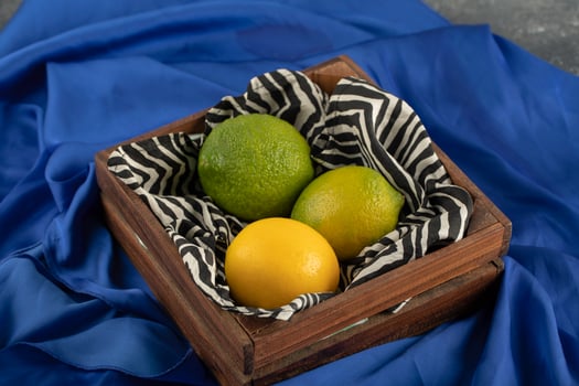 A wooden basket with three lemons on a blue cloth photo