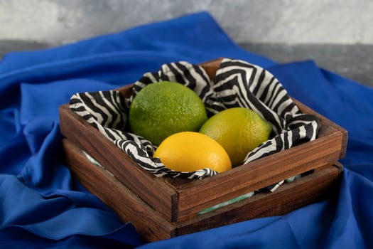 A wooden basket with three lemons on a blue cloth photo