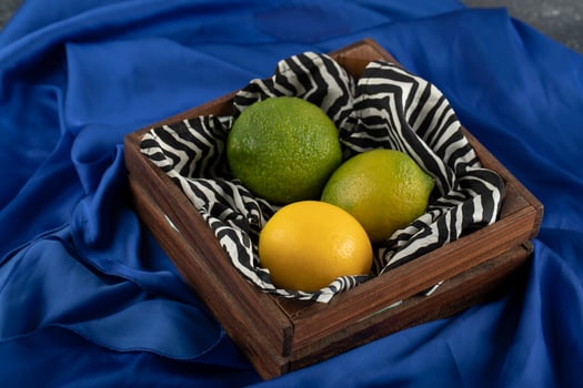 A wooden basket with three lemons on a blue cloth photo