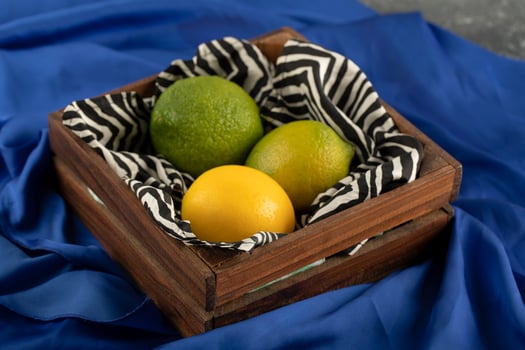 A wooden basket with three lemons on a blue cloth photo