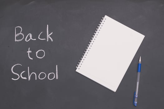 A white notebook with a pen on a chalkboard, back to school and education concept photo