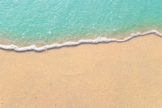 Soft waves with foam of blue ocean on the sandy beach photo