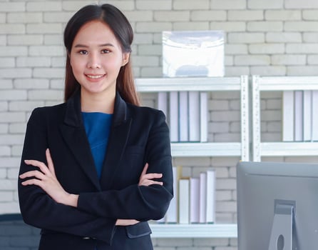 Beautiful young Asian businesswoman stands smiling with happiness in office photo