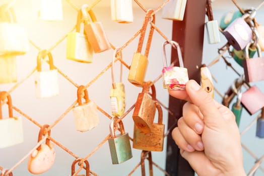 Woman's hand holding a lock on a bridge rail fence photo