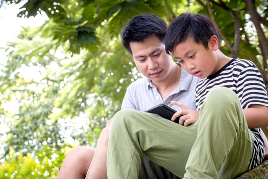 Father and son reading outside photo