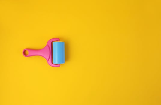 Paint roller against clean yellow background with copy space for text message. Conceptual image. photo