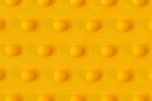 Yellow golf balls on yellow background creative concept. Monochrome color scheme. Repetitive texture pattern. photo