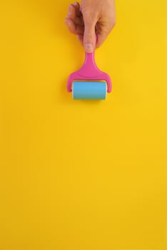 Concept of male hand holding paint roller against clean yellow background with copy space for text message. photo