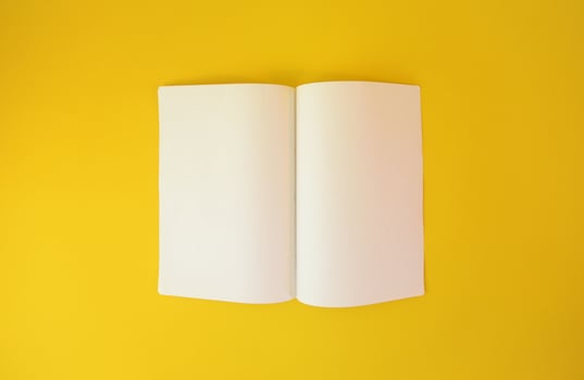 Opened two pages of a notebook on yellow background. Copy space paper for photo or text message.