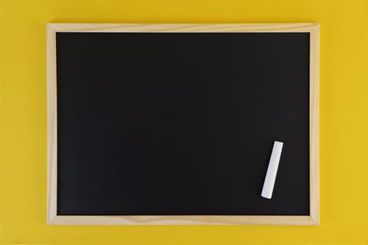 Empty black chalkboard on yellow background. Front view on black chalkboard with wooden frame. Empty copy space on flat panel. photo
