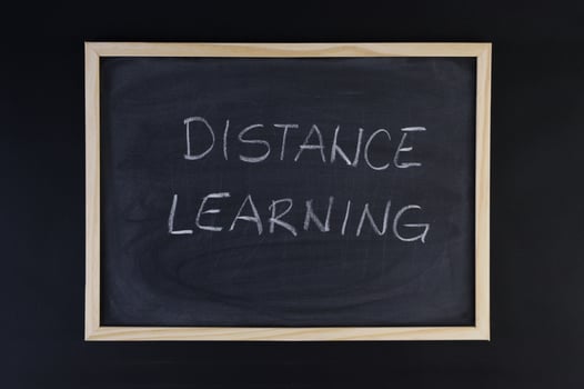 Hand-drawn title Distance Learning on a black chalkboard with wooden frame. photo