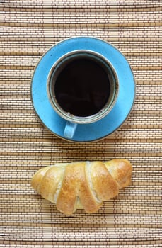 Coffee cup and fresh croissant isolated on vintage textured brown background. Top view on fresh breakfast with coffee and baked sweet pastries. photo