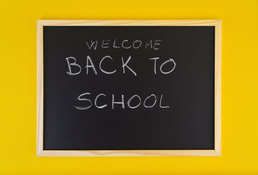 Hand-drawn title Welcome Back to School on black chalkboard among yellow vivid background. photo