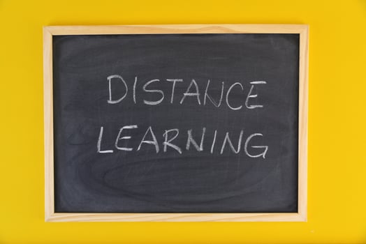 Hand-drawn title Distance Learning on black chalkboard among yellow vivid background. photo
