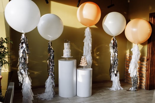 Decoration for birthday with a two-story cake and big white and beige balloons with tinsel. Candy bar with macaroon or macarons. Birthday party. Selective focus. photo
