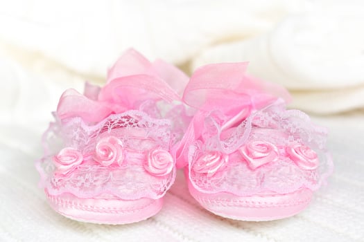 Pink baby booties on white crochet blanket. photo