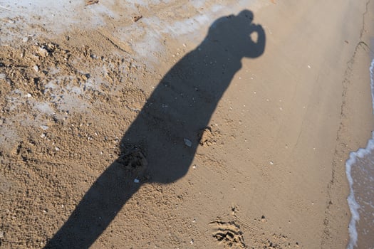Silhouette of a person taking a photograph at the beach photo