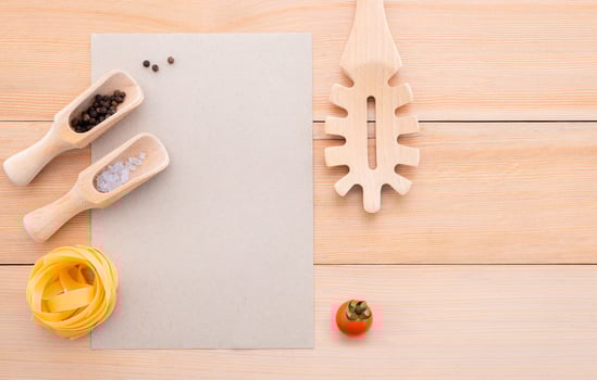 Blank paper and pasta ladle on wooden background photo