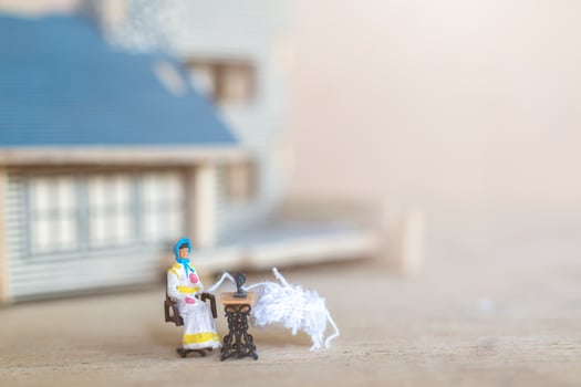 Miniature people, woman sewing on a sewing machine at her home. Woman seamstress working on a sewing-machine photo